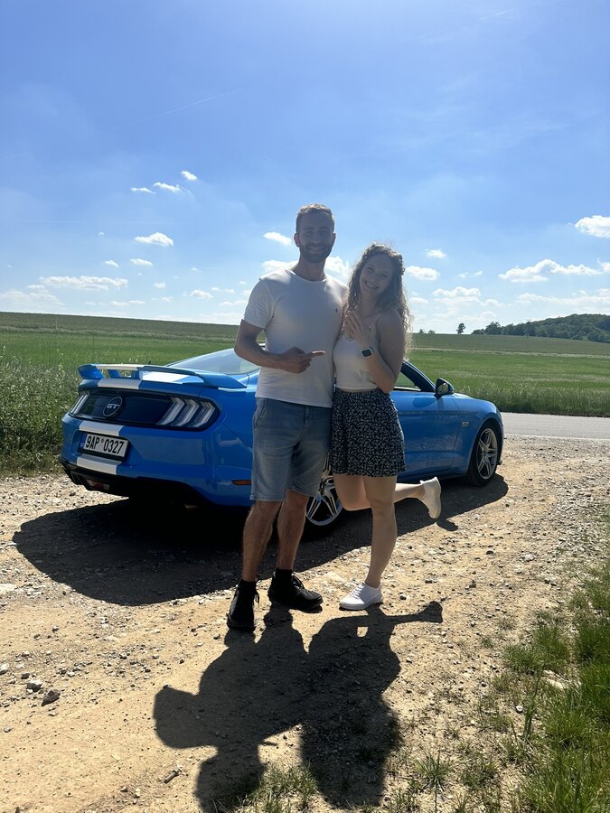 Snoubec a snoubenka s modrým nebem a Mustangem